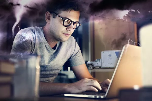 Man on a computer with a FEMA truck in the background